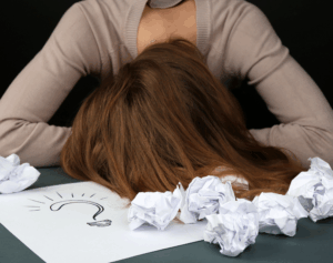 mulher cansada de tentar ideias e colocando a cabeça na mesa