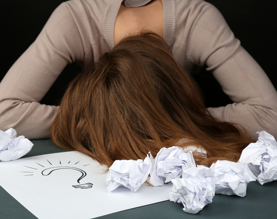 mulher cansada de tentar ideias e colocando a cabeça na mesa